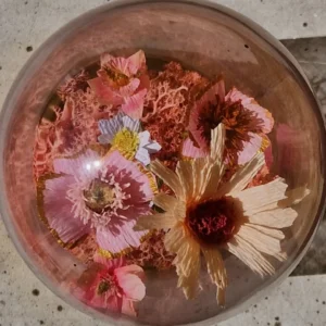 Smuk borddekoration med håndlavede papirblomster under glasklokke